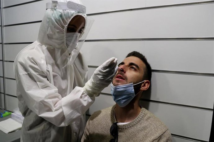 Archivo - Un sanitario practica a un joven una prueba de detección del coronavirus. 