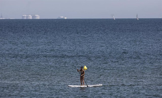 Una mujer hace padelsurf en la Playa de la Malvarrosa, a 12 de agosto de 2022