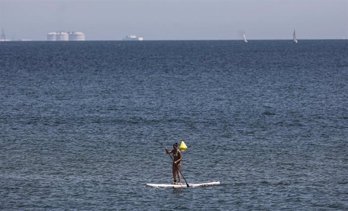 Una mujer hace padelsurf en la Playa de la Malvarrosa, a 12 de agosto de 2022