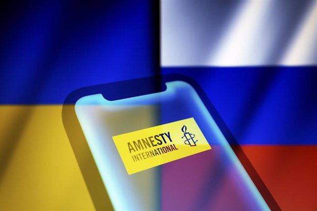 Archivo - Banderas de Ucrania y Rusia junto a un logotipo de Amnistía Internacional