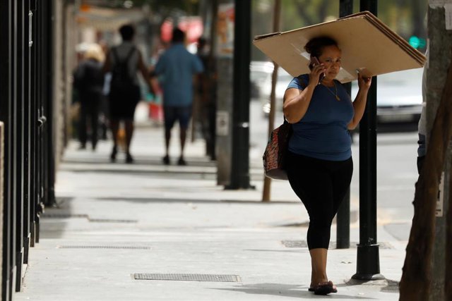 Archivo - Una mujer se protege del sol con una caja de cartón durante un día de alerta roja por altas temperaturas, a 12 de julio de 2021, en la ciudad de Murcia, Murcia (España). 