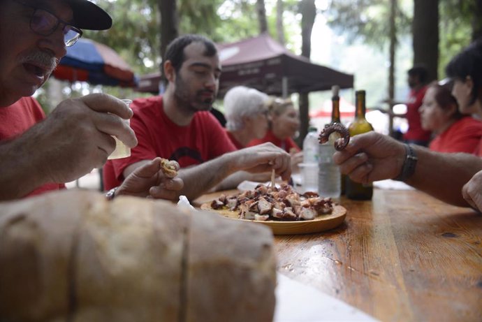 Un grupo de personas comen pulpo en la fiesta de O Carballiño.