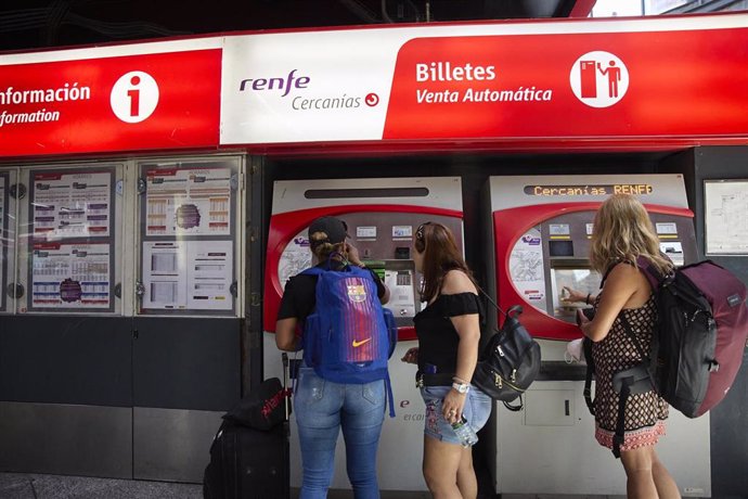 Varias personas en una máquina de venta de billetes en la estación Madrid-Atocha Cercanías, en Madrid (España).