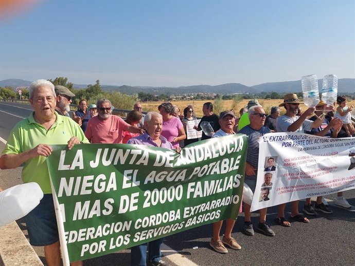 Representantes de la Federación Córdoba Extrarradio se concentran, con botellas en mano, en la carretera N-432, en la Carrera del Caballo, en el término de Córdoba.