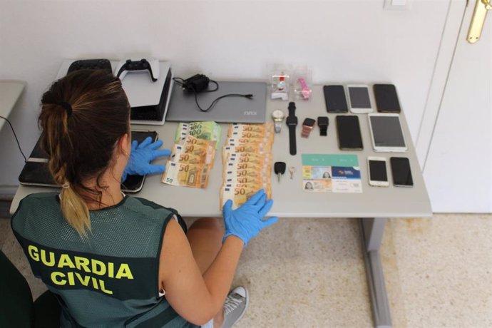 Una agente de la Guardia Civil junto a los efectos robados.