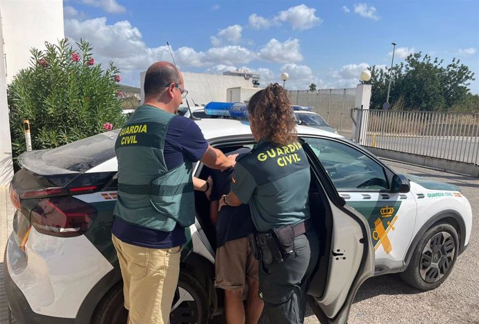 Agentes de la Guardia Civil meten en el coche al detenido.