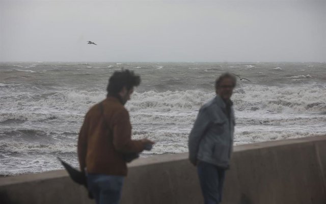 Archivo - Dos personas caminan en la Playa de la Malvarrosa