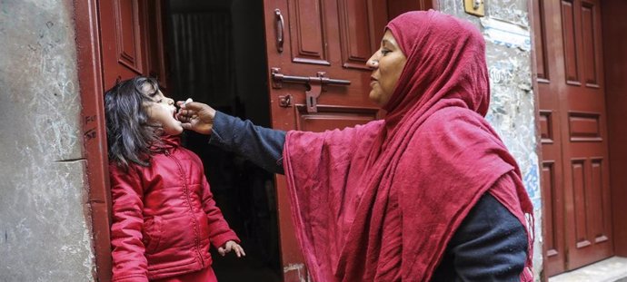 Archivo - Una trabajadora sanitaria vacuna a una niña de 4 años contra la polio en la puerta de su casa en el área de Lahore, en Pakistán.