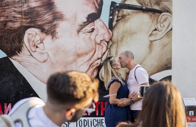Archivo - 11 August 2020, Berlin: Olga and Cristobal have kiss in front of the fraternal kiss mural of Erich Honecker and Leonid Brezhnev at the East Side Gallery. On 13 August 1961, construction of the Berlin Wall began, dividing Berlin for more than 28 