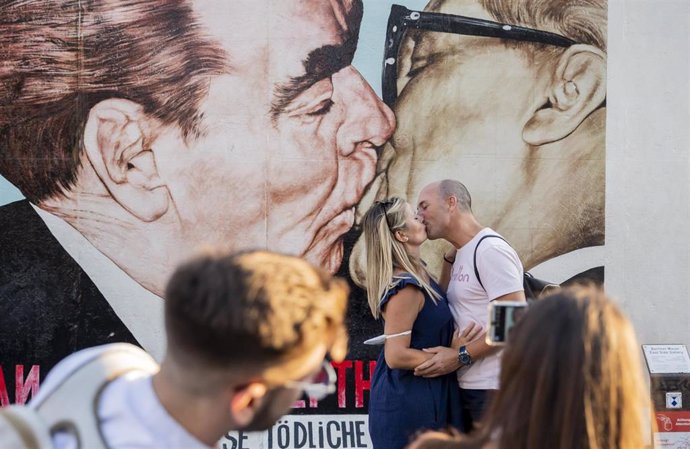 Archivo - 11 August 2020, Berlin: Olga and Cristobal have kiss in front of the fraternal kiss mural of Erich Honecker and Leonid Brezhnev at the East Side Gallery. On 13 August 1961, construction of the Berlin Wall began, dividing Berlin for more than 2