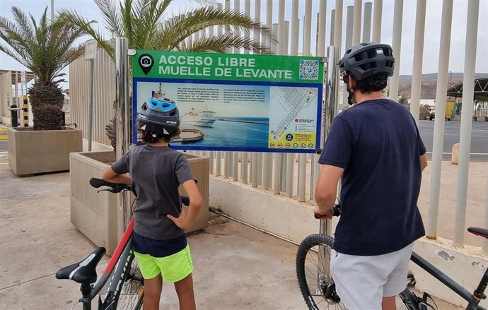 Unos usuarios contemplan el nuevo panel informativo de acceso al Muelle de Levante del Puerto de Almería.