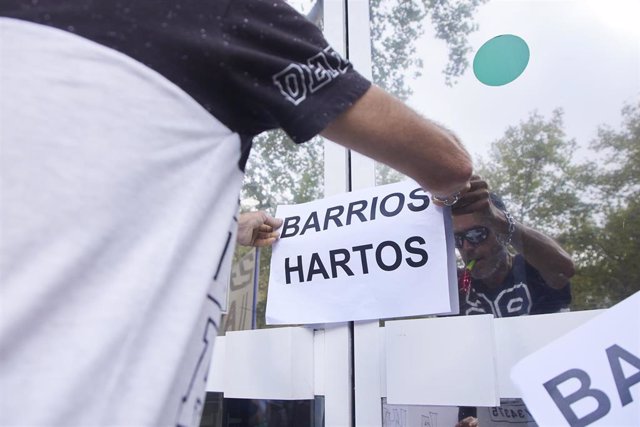 Un vecino coloca un cartel en la puerta de la oficina durante la protesta del colectivo Barrios Hartos protesta frente a la sede de Endesa, a 4 de agosto de 2022 en Sevilla (Andalucía, España)
