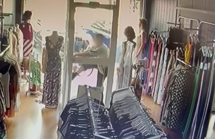 Uno de los ladrones forzando la puerta de la tienda.