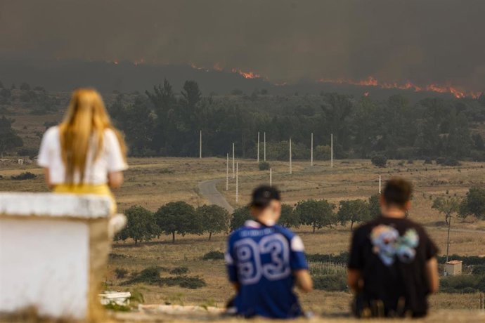 Varias personas observan las llamas y el humo del incendio en Bejís desde el municipio de El Toro