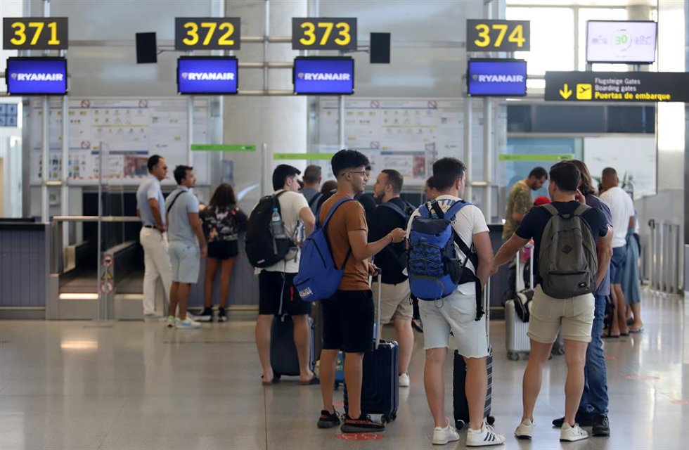 Cientos de turistas hacen colas en los puestos de embarque de Ryanair, en el Aeropuerto Costa del Sol, Andalucía.
