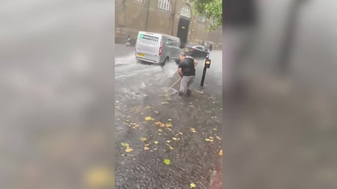 Hay cosas que es mejor tomárselas con humor: así trataba de limpiar este hombre mientras caía un chaparrón