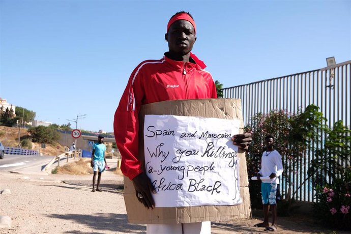 Archivo - Un migrante de origen subsahariano con un cartel, durante una concentración en las inmediaciones del CETI para protestar por los hechos ocurridos el pasado 24 de junio en Melilla, a 27 de junio de 2022, en Melilla (España)