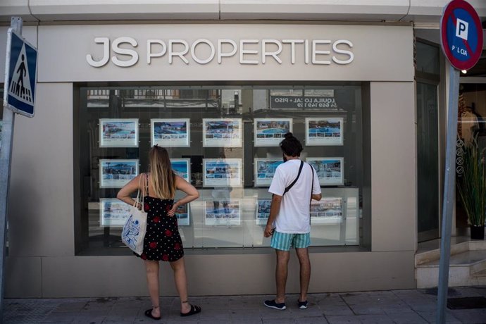 Archivo - Dos personas observan inmuebles en alquiler y en venta en un escaparate de una inmobiliaria ubicada en Palma.