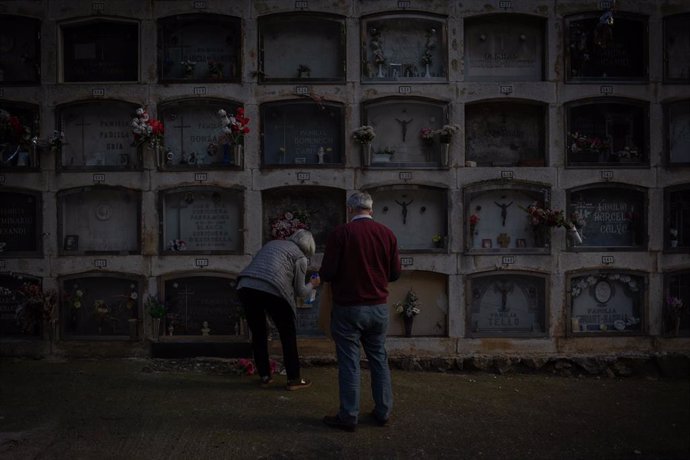 Archivo - Dos personas colocan flores en un nicho del Cementerio de Montjuic, en Barcelona, Catalunya (España), a 27 de octubre de 2020.