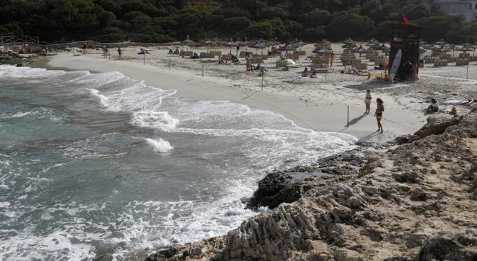 Archivo - 02 September 2021, Spain, Manacor: People stand at the beach of Cala Mendia in Manacor on Mallorca, which cordoned off with a tape. Photo: Clara Margais/dpa