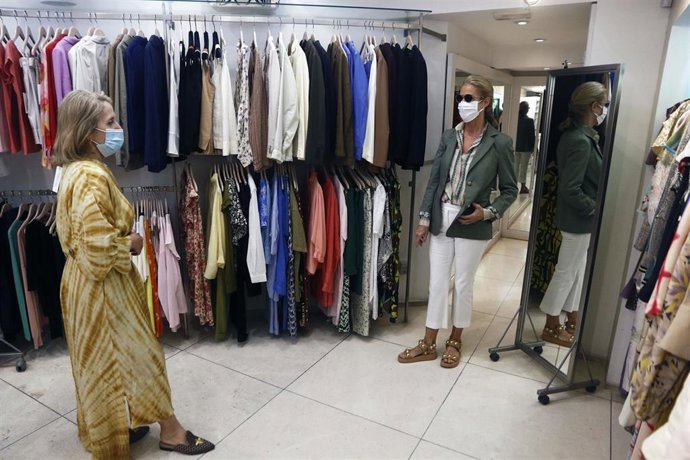 Archivo - Una dependienta de un comercio de ropa