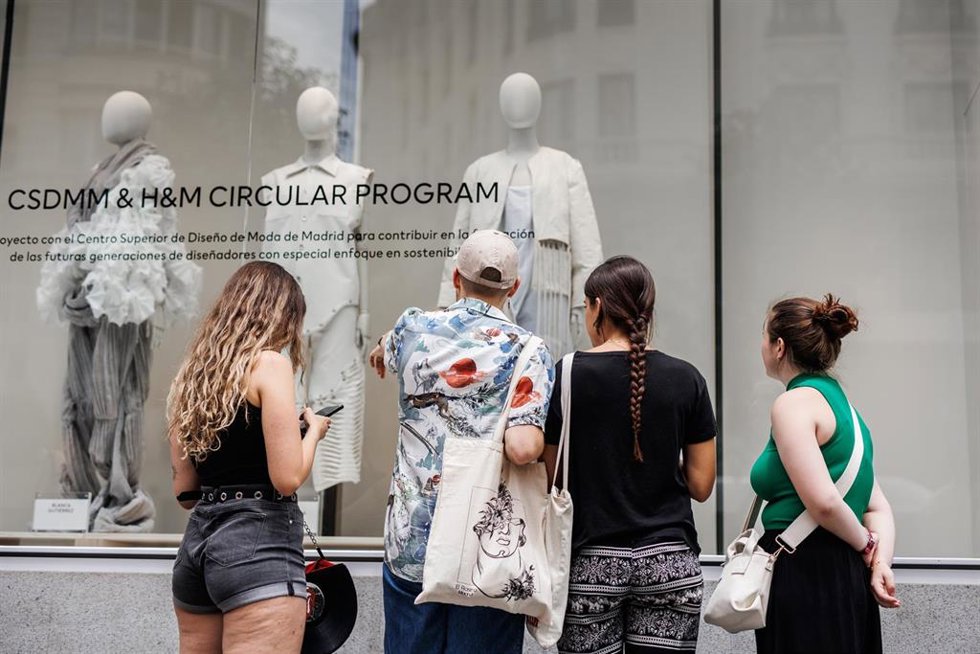 Archivo - Varias personas observan un escaparate de H&M