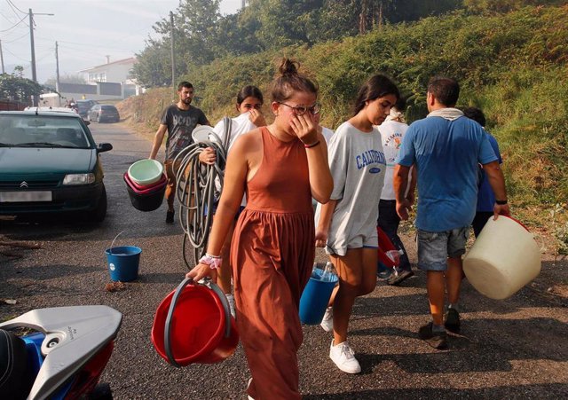 Varios vecinos de la parroquia de Meira con cubos de agua para sofocar el fuego, a 22 de agosto, en la parroquia de Meira, en Moaña, Pontevedra, Galicia (España). El fuego declarado en una zona de eucaliptos, ha obligado a cortar la autovía de O Morrazo e