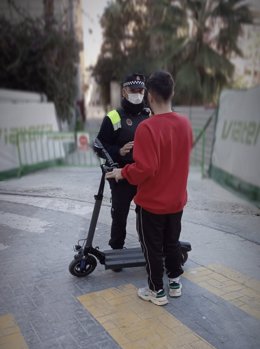 Archivo - Un policía local conversa con el usuario de un patinete eléctrico.