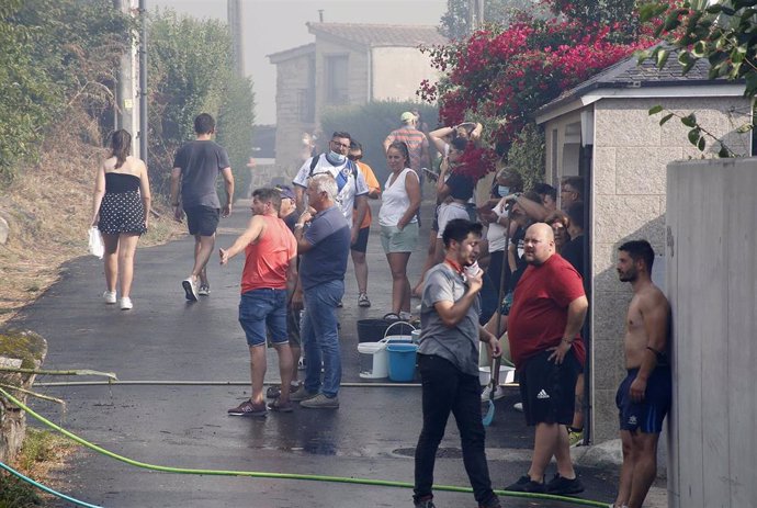 Los vecinos de la parroquia de Meira con cubos de agua y mangueras para sofocar el fuego, a 22 de agosto, en la parroquia de Meira, en Moaña, Pontevedra, Galicia (España). El fuego declarado en una zona de eucaliptos, ha obligado a cortar la autovía de 