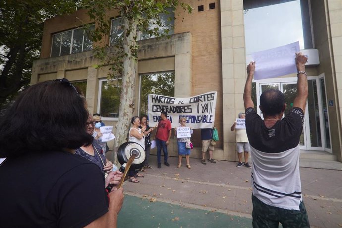 Un hombre levanta una pancarta frente a las oficinas de Endesa mientras una mujer hace ruido con una sartén durante la protesta del colectivo Barrios Hartos protesta frente a la sede de Endesa, a 4 de agosto de 2022 en Sevilla (Andalucía, España)