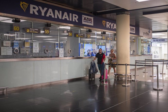Dos personas pasan junto a una ventanilla de Ryanair en el Aeropuerto Josep Tarradellas Barcelona-El Prat, a 8 de agosto de 2022, en Barcelona, Catalunya (España). Se reanudan hoy las nuevas jornadas de huelga de los tripulantes de cabina de pasajeros (