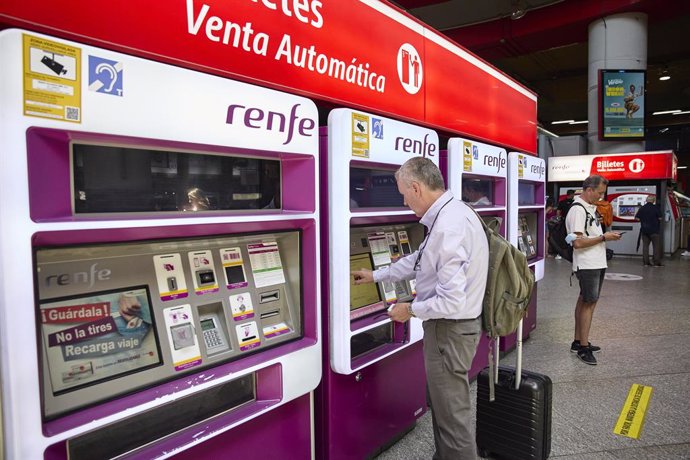Una persona en una de las máquinas de venta de billetes en la estación Madrid-Atocha Cercanías, en Madrid (España). 