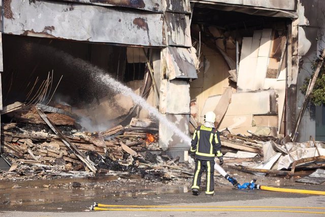 Bomberos durante las labores de extinción de una nave en Utrera, en Sevilla.