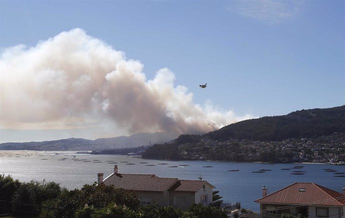 Un helicóptero al lado de una columna de humo en el incendio de Moaña (Pontevedra)