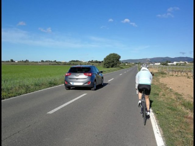 Un ciclista i un vehicle circulant per una carretera