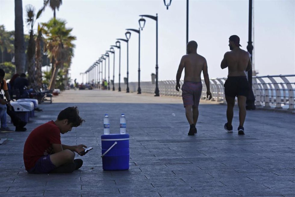 Un niño vende botellas de agua en un puesto improvisado en el paseo marítimo de Beirut, Líbano.
