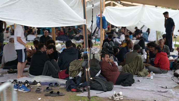 26 August 2022, Netherlands, Ter Apel: Asylum seekers sit in the vicinity of the national asylum centre Ter Apel. Hundreds of asylum seekers have been sleeping in the open air for weeks in the vicinity of the facility, after the border with Lower Saxony