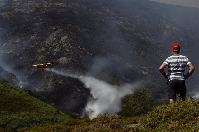 Un vecino de Senderiz en Lobeira observa un hidroavión trabajar en el incendio forestal en la Serra do Leboreiro, sobrevuela una explotación ganadera, en el parque natural de Baixa Limia e Serra do Xurés, a 26 de agosto de 2022, en Serra do Xurés, Ouren