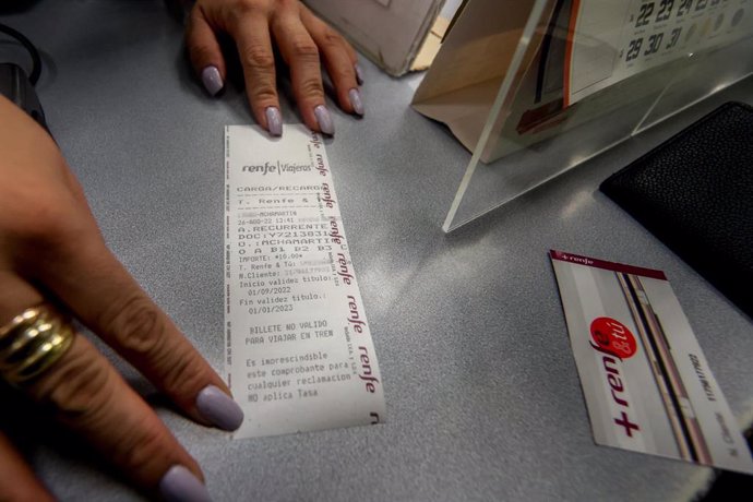 Una trabajadora muestra el ticket a un viajero tras cargarle la tarjeta Renfe con el abono gratuito