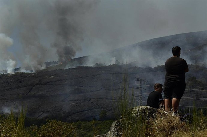 Dos personas de Grou observan el incendio forestal en la Serra do Leboreiro, en Senderiz, en el parque natural de Baixa Limia e Serra do Xurés, a 26 de agosto de 2022, en Serra do Xurés, Ourense, Galicia (España). La superficie afectada por el incendio 