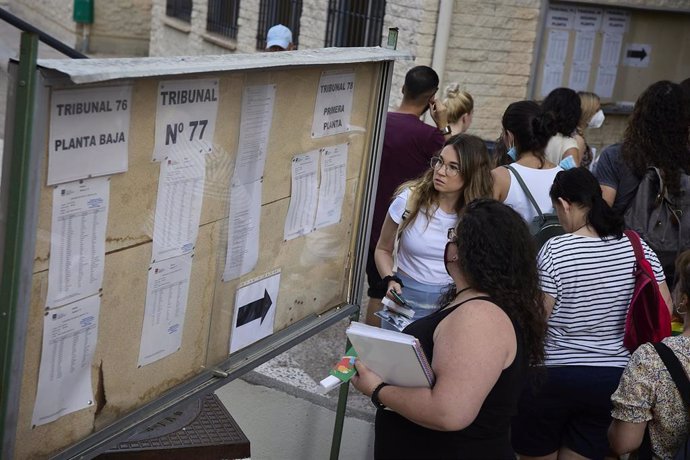 Archivo - Varias personas en un instituto de Leganés (Madrid) miran los carteles con indicaciones para realizar las pruebas para acceder a plazas de docentes.