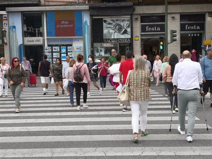 Archivo - Personas cruzando en un semáforo del centro de Santander