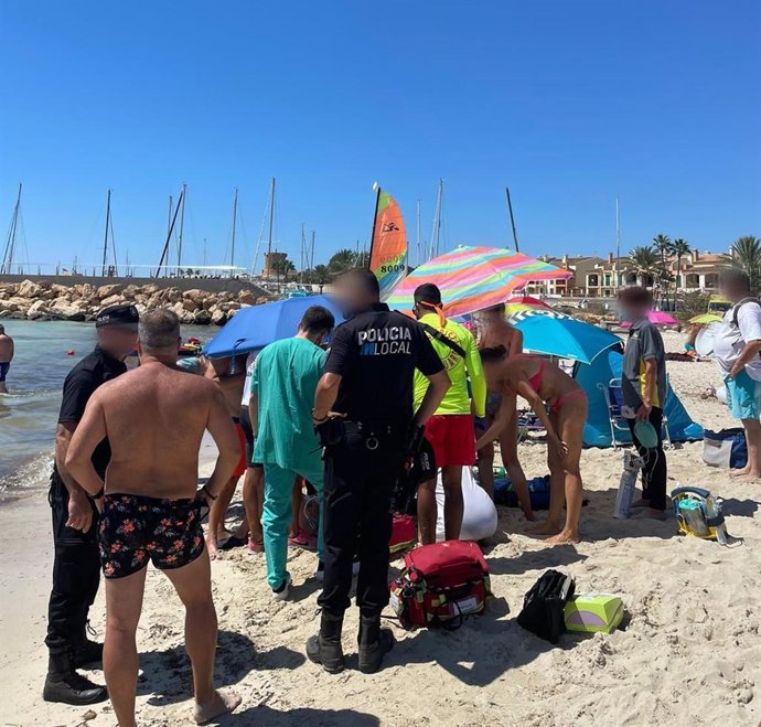 Varias personas en la orilla de una playa de Campos donde se está reanimando a la mujer.