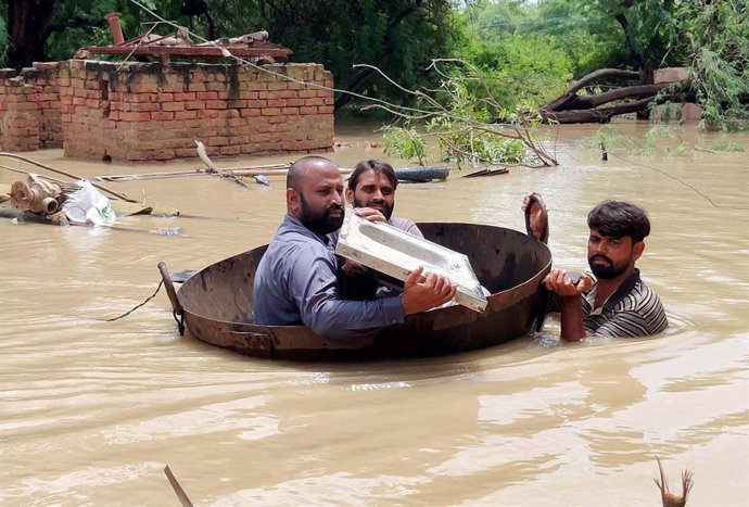 26 August 2022, Pakistan, Sukkur: Residents cross a flooded area in a makeshift boat amid floods caused by heavy downpours. Photo: -/PPI via ZUMA Press Wire/dpa
