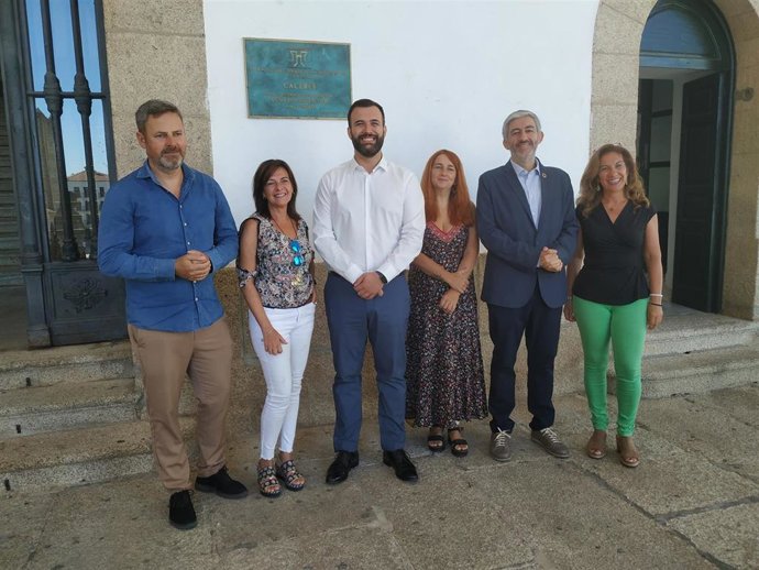Miembros del equipo de gobierno y técnicas de turismo y cultura bajo la placa que recuerda el nombramiento de Cáceres como Ciudad Patrimonio de la Humanidad