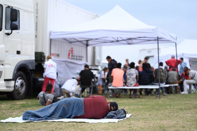 26 August 2022, Netherlands, Ter Apel: A man rests in front of a treatment station of the organization "Doctors without Borders" which was built at the national asylum centre Ter Apel. Hundreds of asylum seekers have been sleeping in the open air for we
