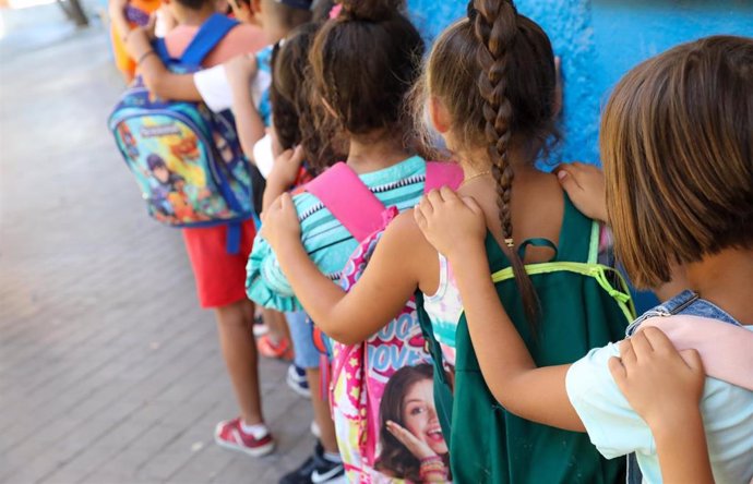 Varios niños hacen fila con sus mochilas, antes de entrar al Centro Chapotea con la Asociación Barró en Vallecas, a 20 de julio de 2022, en Madrid (España). Este centro pertenece al programa CaixaProinfancia que facilita que 35 entidades de la Comunidad