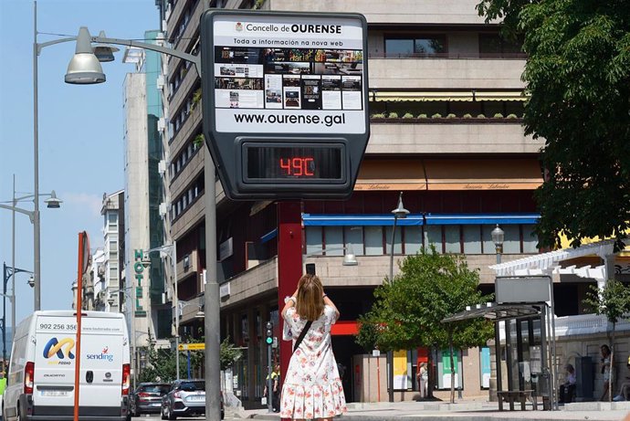 Archivo - Una mujer hace una fotografía a un termómetro en la calle que marca 49 grados, en Orense.