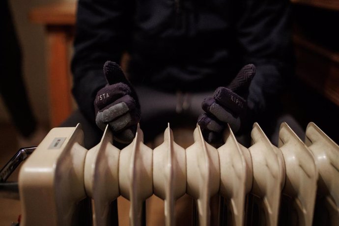 Archivo - Una persona calienta las manos en un radiador eléctrico.