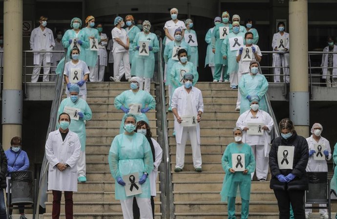 Archivo - Sanitarios protegidos con mascarillas sujetan crespones negros durante el minuto de silencio en la entrada del Hospital Doctor Peset por la técnica de enfermería fallecida por coronavirus, en Valencia/Comunidad Valenciana (España) a 6 de abril